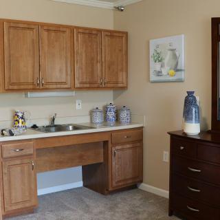 A small kitchenette with wooden cabinets, a sink, and decorative elements.