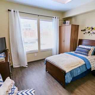 A cozy and well-lit bedroom with a single bed and modern furnishings.
