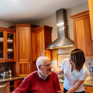 An elderly person receiving care in a kitchen setting.