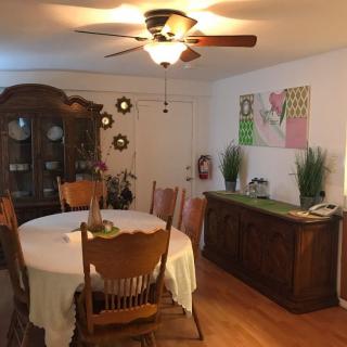 A cozy dining room with a wooden table, chairs, and a ceiling fan.