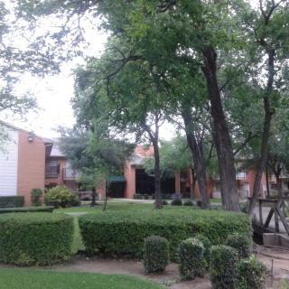 A view of an apartment complex surrounded by well-maintained landscaping and trees.