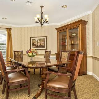 A classic dining room with a wooden table and chairs, illuminated by a chandelier.