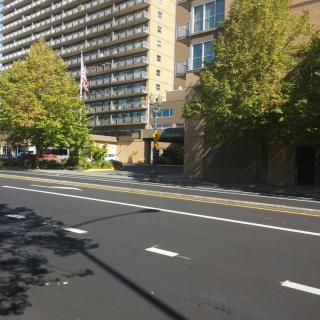 A street view featuring a high-rise building surrounded by trees.