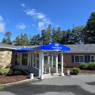 A welcoming entrance with a blue canopy surrounded by greenery.