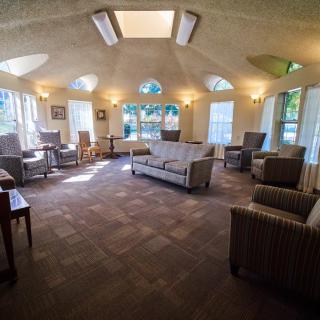 A spacious living room with ample seating, large windows, and natural light streaming in.