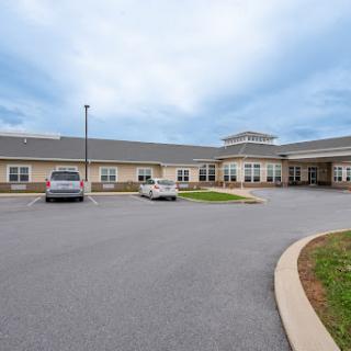 A healthcare facility with a spacious parking lot under a cloudy sky.