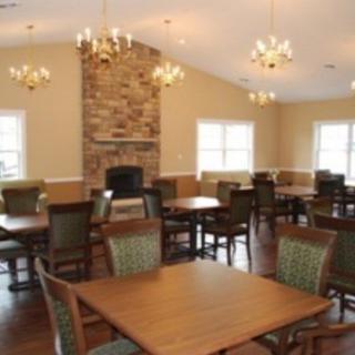 A cozy dining room with wooden tables and chairs, featuring a stone fireplace and chandeliers.