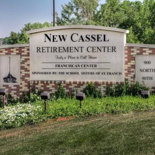 Entrance sign for New Cassel Retirement Center surrounded by greenery.