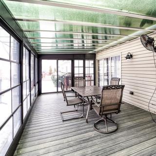 A spacious sunroom with a glass roof, featuring a dining table and chairs for outdoor relaxation.