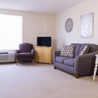 A minimalist living room with a sofa, armchair, and TV.