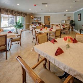 A well-lit dining area with neatly arranged tables and chairs, featuring elegant table settings with red napkins.