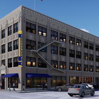 A four-story urban building with cars parked on the street.