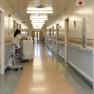 A hospital corridor with a nurse attending to a cart.