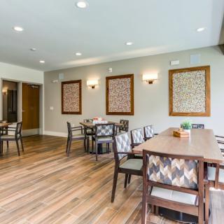 A modern dining area featuring wooden floors, stylish chairs, and decorative wall art.