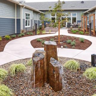 A landscaped courtyard with a winding pathway, surrounded by plants and modern architecture.