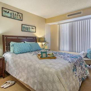 A cozy bedroom with a neatly made bed, decorated with patterned pillows and a bedside lamp, creating a warm and inviting atmosphere.