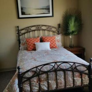 A cozy bedroom with a metal-framed bed, decorative pillows, and a piece of artwork on the wall.