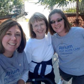 Three women smiling together outdoors.