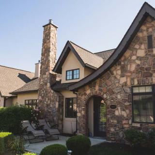 A charming stone house with a chimney and well-kept garden.