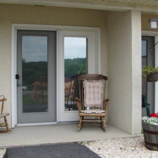 A cozy patio with rocking chairs and decorative plants by the door.