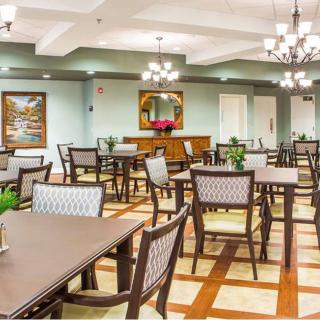 A well-lit dining room with neatly arranged tables and chairs, elegant chandeliers, and tasteful decor.