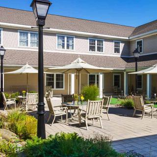 A sunny outdoor patio area with tables and umbrellas in front of a building.