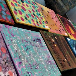 A vibrant display of abstract paintings on canvas, showcasing a variety of colors and patterns.