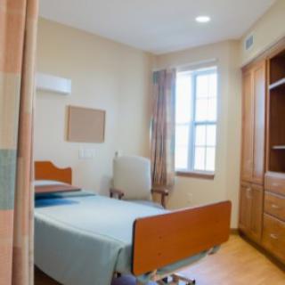 A bright and simple bedroom featuring a single bed and wooden furniture.