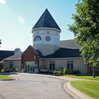 A charming community building with a distinctive tower, surrounded by lush greenery.