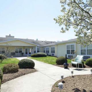 A sunny view of a residential building with a landscaped garden and pathway.