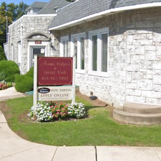 An office building featuring a stone exterior and a prominent business sign in the foreground.