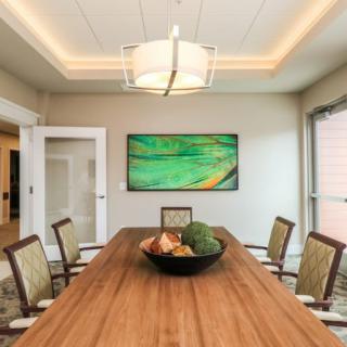 A modern dining room featuring a large wooden table, stylish chairs, and contemporary artwork.
