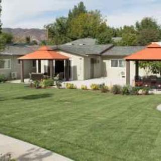 A charming house with a well-maintained lawn and two gazebos in a residential neighborhood.