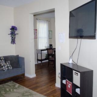 A cozy living room with a wall-mounted TV and a view into the home office.