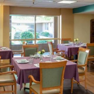 A cozy dining area with elegantly set tables and chairs near a large window.