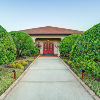 A beautifully landscaped entrance to a home, featuring well-manicured bushes and a welcoming pathway.