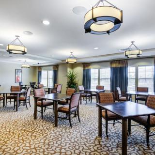 A well-lit dining area with multiple tables and chairs arranged on a patterned carpet.