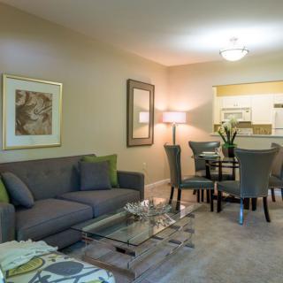 A modern living room with a cozy sofa and a dining area in the background.