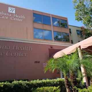 Exterior view of a healthcare facility with palm trees in the foreground.