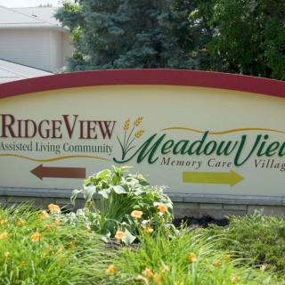 Entrance sign for RidgeView Senior Living Community and Meadow View Memory Care Village with directional arrows.