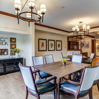 A stylish dining room featuring a large table, elegant chandeliers, and decorative wall art.