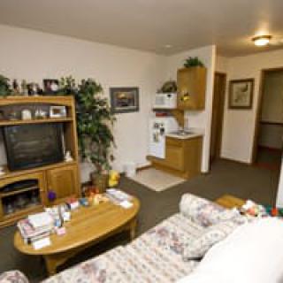 A cozy living room with a TV and kitchenette, featuring a floral sofa and a coffee table.