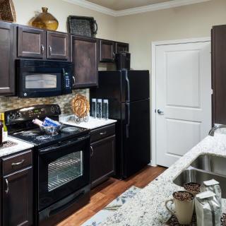 A modern kitchen with dark cabinets and various appliances.