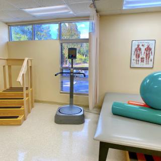 A well-equipped physical therapy room featuring exercise equipment, a staircase for rehabilitation exercises, and an exercise ball.