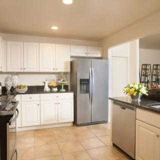 A modern kitchen with white cabinets and stainless steel appliances.