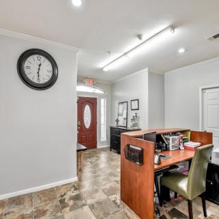 An office reception area with a desk, chairs, and a wall clock.