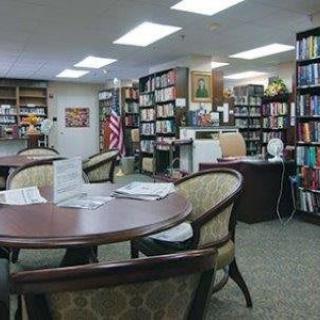 A cozy library reading area with tables, chairs, and bookshelves filled with books.