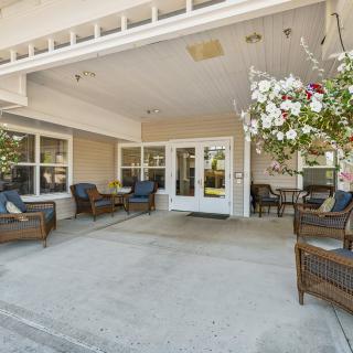 A welcoming patio area with wicker furniture and flower arrangements at the entrance.