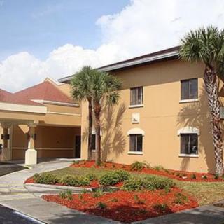 A view of a hotel building with palm trees and landscaped surroundings.