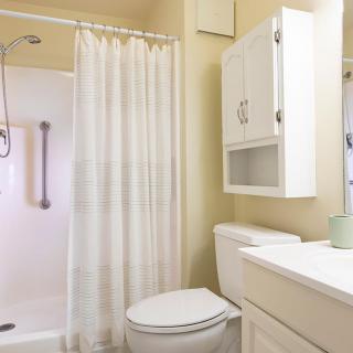 A clean and tidy bathroom with a shower, toilet, sink, and cabinet.